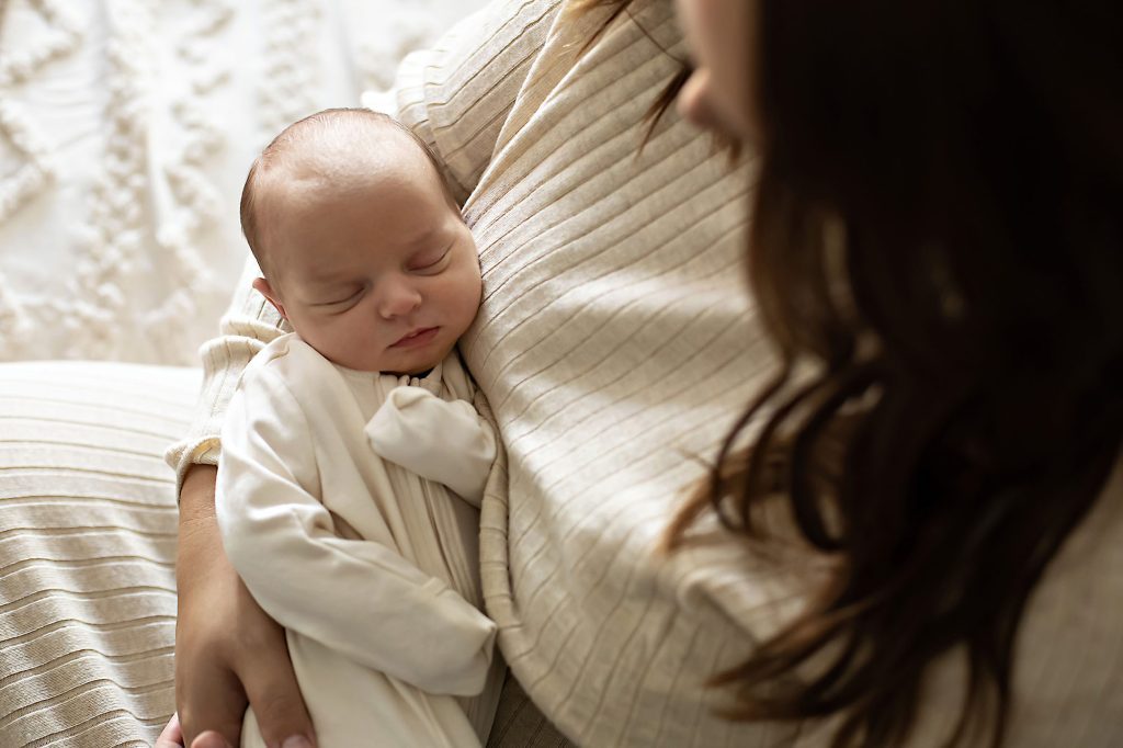 Newborn sleeping in parent's arms at home
