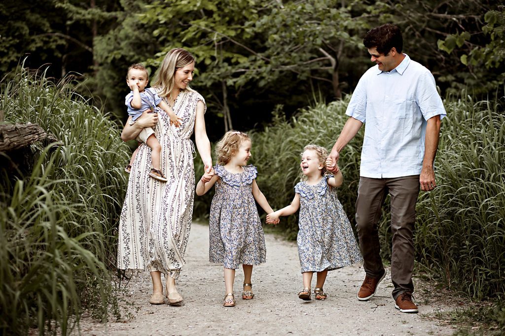 Family walking on forest path, parents with two daughters and a baby