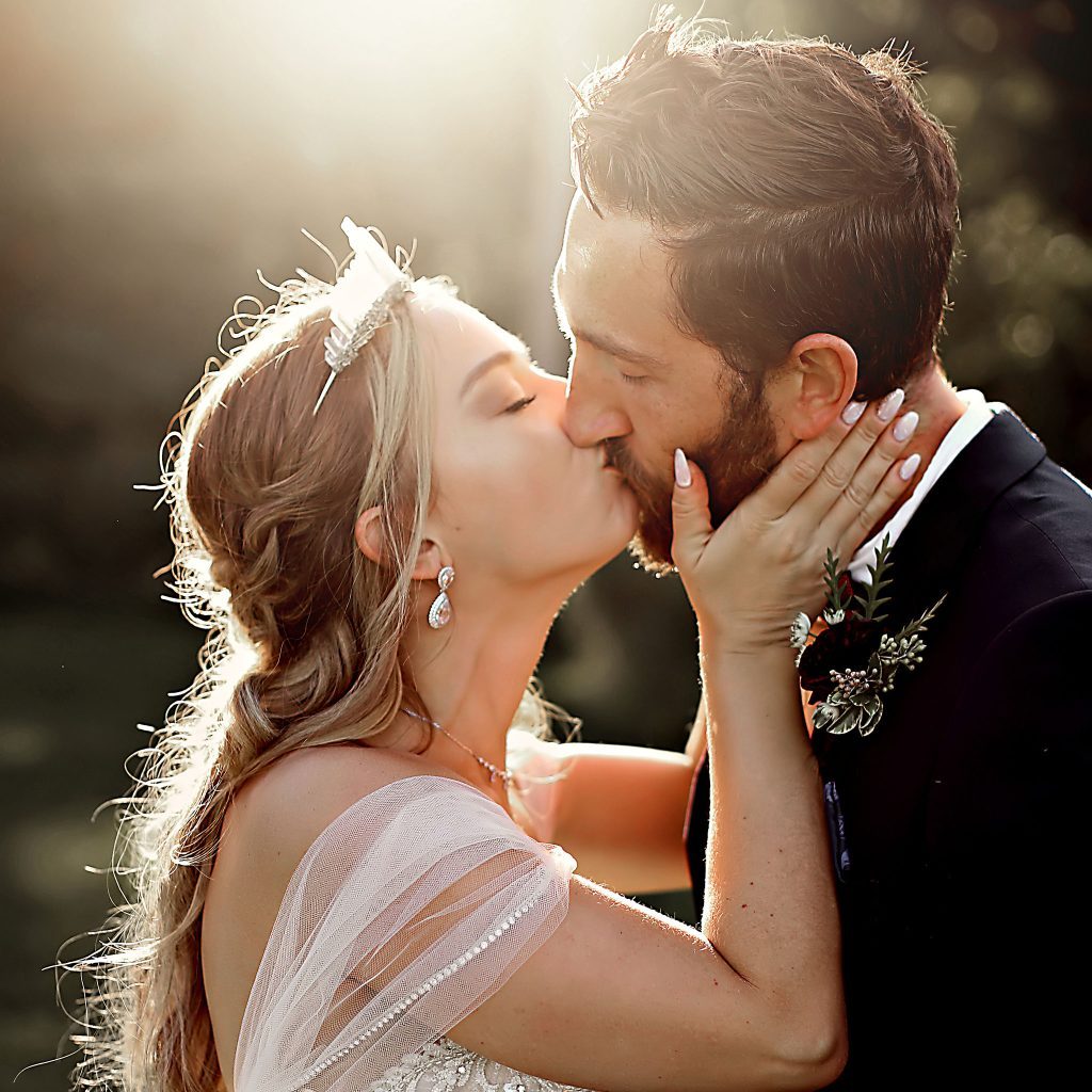 Bride and groom share a romantic kiss at sunset