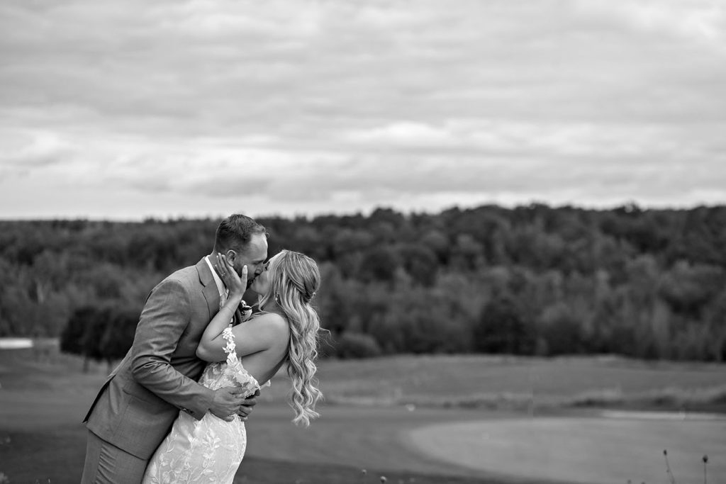 Bride and groom kissing on a scenic golf course