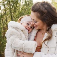 Mother and daughter smiling in matching winter coats outdoors